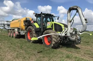 Traktor Claas s cisternou a aplikátorem kejdy na poli