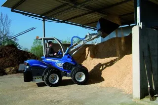 Modrý kolový nakladač MultiOne u hromady sypkého materiálu