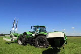 Zelený traktor s žací kombinací SaMASZ na louce.