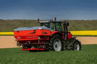 Traktor s červeným rozmetadlem Kuhn na poli