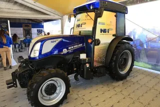 Modrý vinařský traktor New Holland T4.110F NHDrive vystavený v hale.