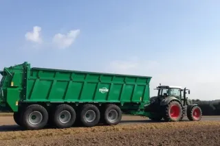 Zelené rozmetadlo Tebbe zapřažené za traktorem