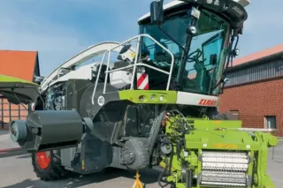 Sklízecí řezačka Claas při údržbě u zemědělské budovy