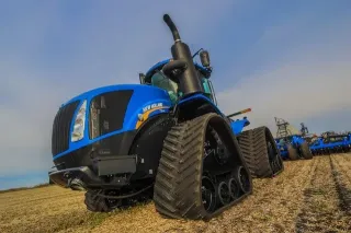 Modrý pásový traktor New Holland na poli