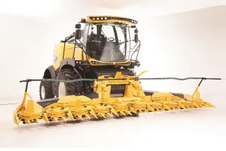 Žlutá sklízecí řezačka New Holland s žacím adaptérem