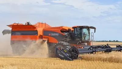 Oranžová sklízecí mlátička Tribine při sklizni obilí