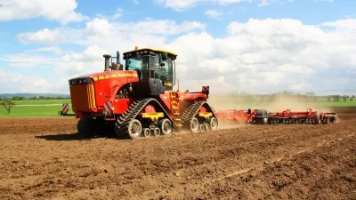 Červený pásový traktor Versatile 610 DT při práci na poli
