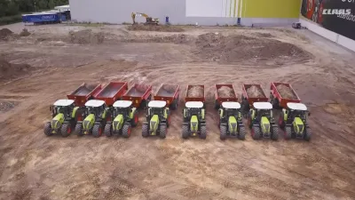 Řada traktorů Claas s vozy u staveniště