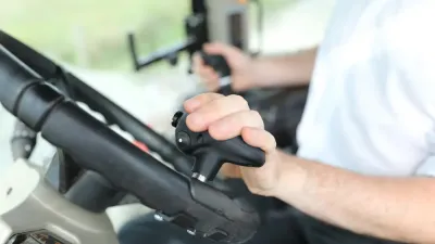 Detail ruky řidiče na ovladači připevněném k volantu traktoru