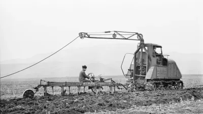 Historická fotografie elektrického traktoru s kabelem při práci na poli