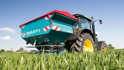 Rozmetadlo Sulky DX W-Control připojené k traktoru na poli