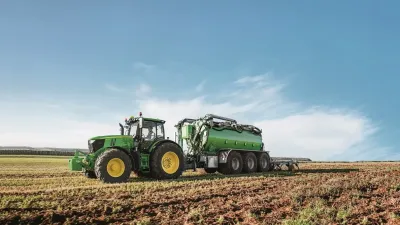Zelený traktor s cisternou John Deere na poli