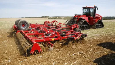 Červený pásový traktor s půdním kypřičem Horsch na poli