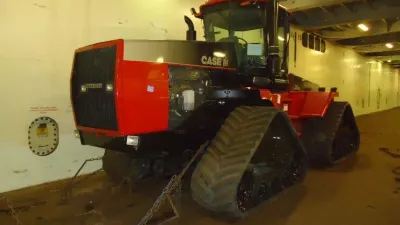 Starší červený pásový traktor Case IH Quadtrac v nákladovém prostoru