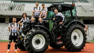 Fotbalisté pózují u traktoru IRUM TAGRO na stadionu