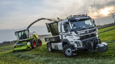 Upravený nákladní vůz Volvo vedle řezačky Claas na poli