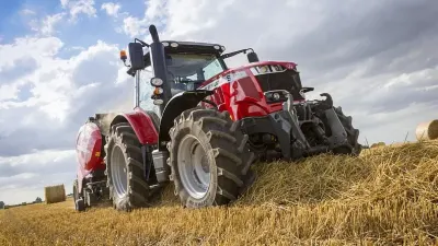 Červený traktor Massey Ferguson s lisem na poli