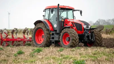 Červený traktor Zetor Crystal s pluhem na poli