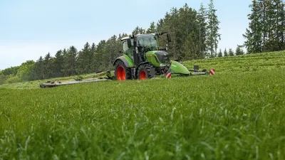 Zelený traktor Fendt se žacím strojem na louce