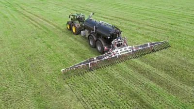 Traktor s černou cisternou a širokým aplikátorem na louce