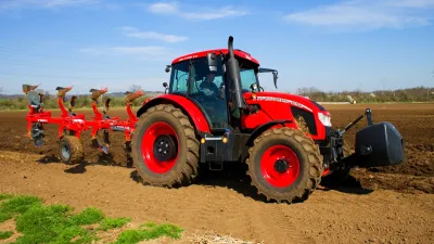 Červený traktor Zetor s pluhem na poli
