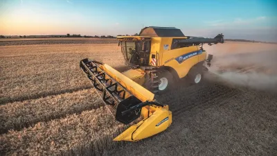 Sklízecí mlátička New Holland v obilí za soumraku