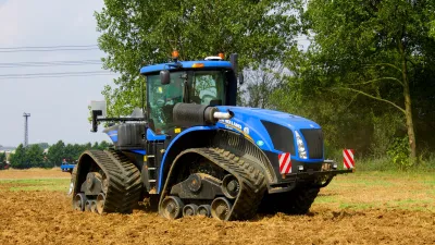 Modrý pásový traktor New Holland při práci na poli