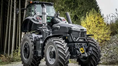 Černý upravený traktor Deutz-Fahr na lesní cestě