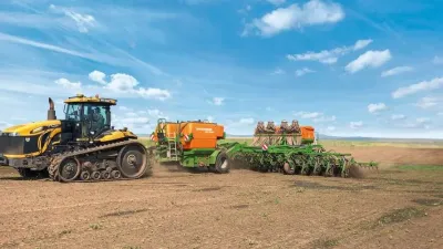 Pásový traktor s přídavným zásobníkem hnojiva Amazone na poli