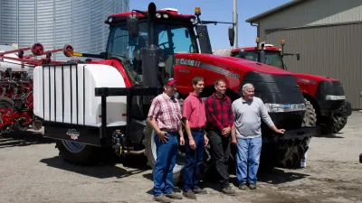 Čtyři farmáři před červenými traktory Case IH na americké farmě