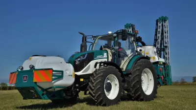 Zelený traktor Arbos s bílou čelní nádrží na poli