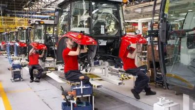 Pracovníci montují červené traktory Massey Ferguson ve výrobním závodě