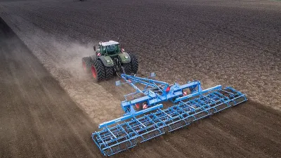 Zelený traktor s modrým kypřičem Lemken na poli
