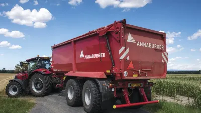 Traktor s červeným návěsem Annaburger na polní cestě