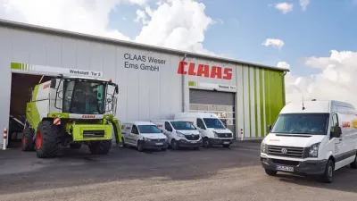 Sklízecí mlátička Claas a servisní vozy před výrobním závodem