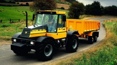 Žlutý traktor JCB Fastrac na louce s ovcemi