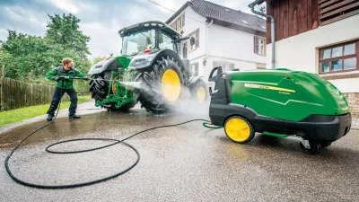 Muž myje tlakovou vodou velký traktor