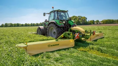 Traktor se žací kombinací Krone na louce