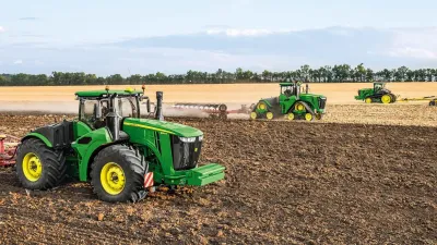 Zelený traktor John Deere při práci na poli