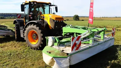 Žlutý traktor JCB Fastrac se žacím strojem na louce