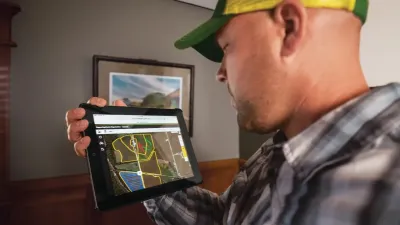 Muž ukazuje aplikaci John Deere Operations Center na tabletu