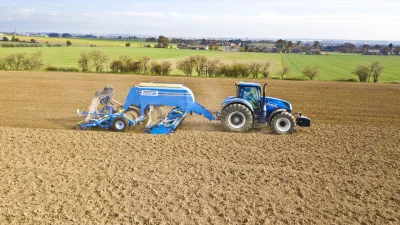 Modrý traktor se secím strojem Farmet Falcon při práci na poli