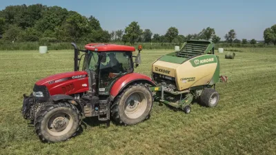 Červený traktor Case IH táhne lis Krone na louce