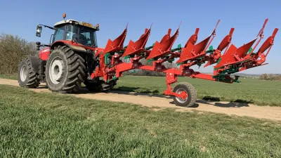 Červený traktor s pluhem Sukov na polní cestě