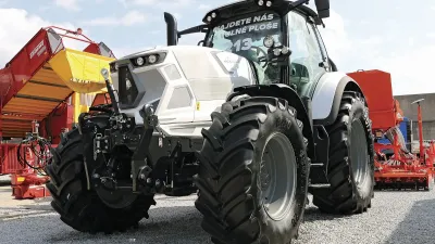 Bílý traktor s pneumatikami Mitas na výstavní ploše.