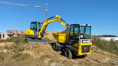 Žluté rypadlo nakládá zeminu do dampru Wacker Neuson