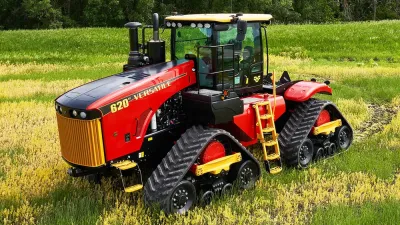 Červený pásový traktor Versatile stojí na poli.