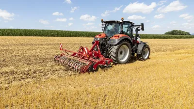 Traktor s červeným diskovým podmítačem Horsch Joker CT na strništi.