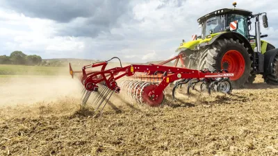 Traktor s červeným kypřičem Horsch Finer pracuje na poli.