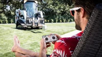 Muž ovládá nakladač Bobcat pomocí mobilního telefonu.